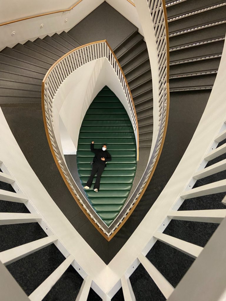 Manda Mutai photographed from above, surrounded by spiraling staircase.